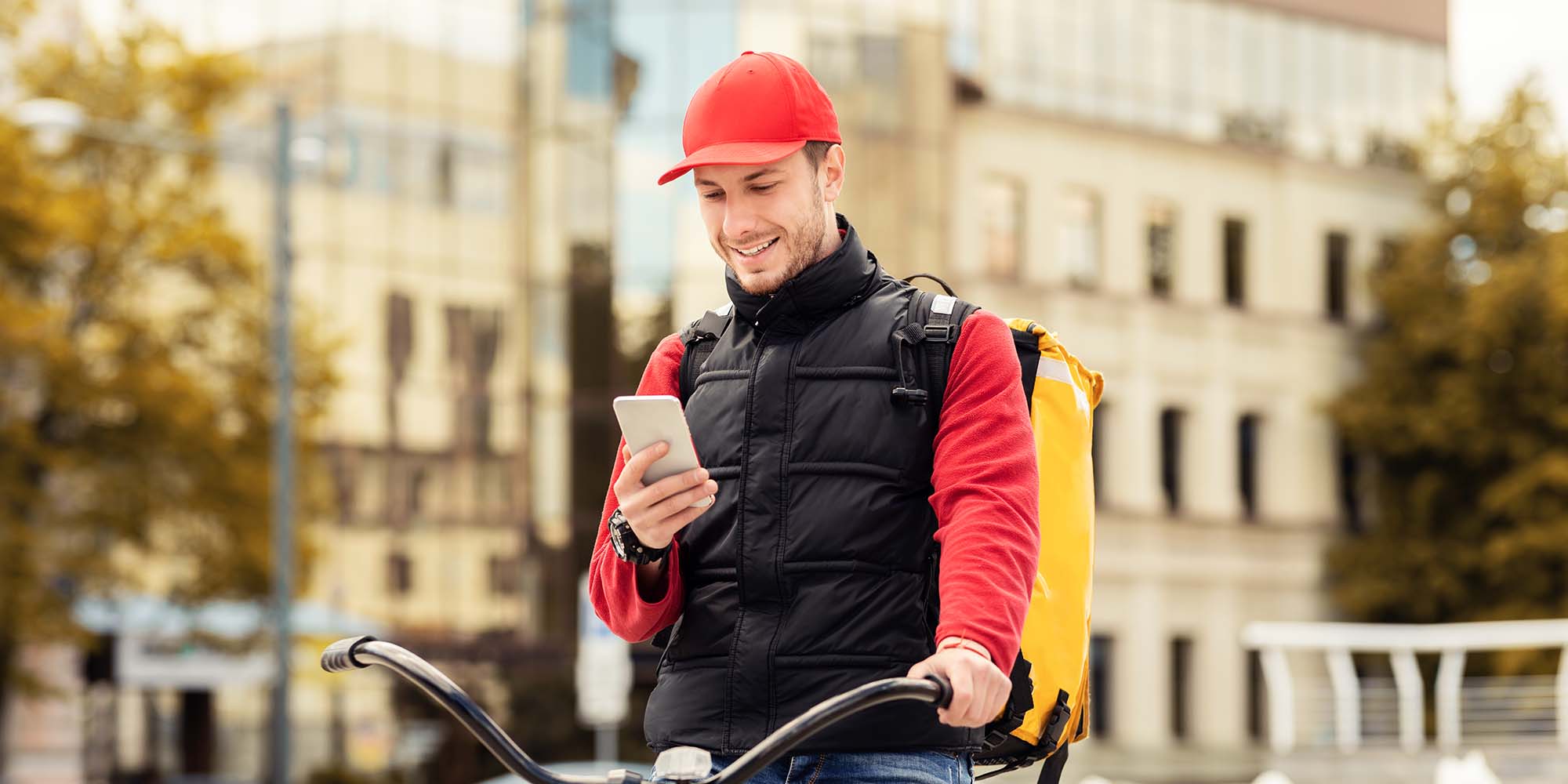 delivery-guy-with-phone-sitting-on-bicycle-using-a-X9U9AJX.jpg